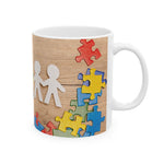 Puzzle Piece Ceramic Mug with colorful puzzle pieces and paper cutout figures, symbolizing inclusion and unity.