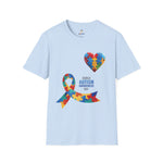 Light blue t-shirt featuring a colorful heart made of puzzle pieces and a multicolored puzzle ribbon with the word “Autism,” symbolizing autism awareness, love, and inclusion.