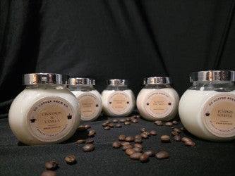 Velas aromáticas artesanales en frascos elegantes con granos de café decorativos.